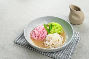 Kue Putu Mayang is traditional Indonesian snack made from rice flour strands curled up into a ball, served with coconut milk and palm sugar. Selected focus. photo