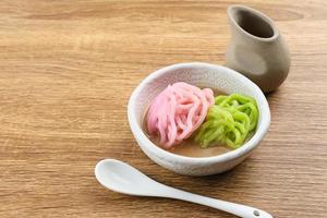 Kue Putu Mayang is traditional Indonesian snack made from rice flour strands curled up into a ball, served with coconut milk and palm sugar. Selected focus. photo