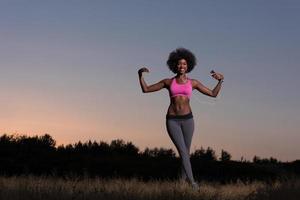 mujer negra está haciendo ejercicio de estiramiento relajándose y calentándose foto