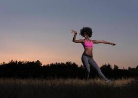 mujer negra está haciendo ejercicio de estiramiento relajándose y calentándose foto