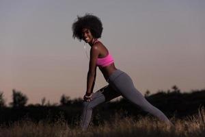 mujer negra está haciendo ejercicio de estiramiento relajándose y calentándose foto