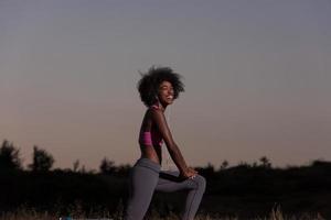 mujer negra está haciendo ejercicio de estiramiento relajándose y calentándose foto