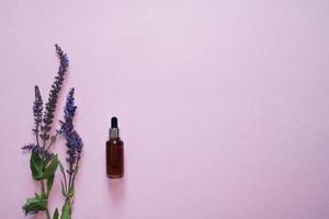 Flat lay composition with lavender flowers and natural cosmetics on a pink background.Bottle with pipette photo