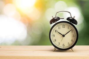 Retro alarm clock on table with green background photo