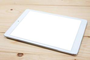 White tablet PC with blank screen on wooden table photo