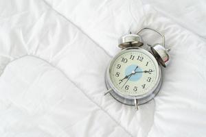 Close up view of alarm-clock in morning on a white bed,Wake up concept photo