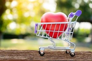 Red Heart Shape On Mini Shopping Cart Over Nature Background photo