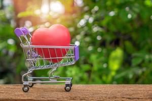 Red Heart Shape On Mini Shopping Cart Over Nature Background photo