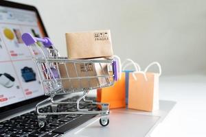 Paper boxes in a trolley  on a laptop computer ,Easy shopping online concept,Online shopping or ecommmerce concept photo