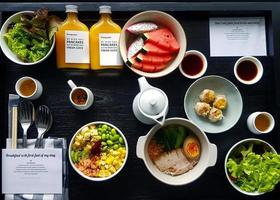 Top view of breakfast with fresh salad, dim sum, noodle with boiled pork, watermelon, dragonfruit, bottle of orange juice and sweet sauce. Flat lay of healthy food with vegetable and fruit on table. photo