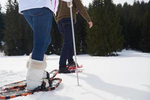 pareja divirtiéndose y caminando con raquetas de nieve foto