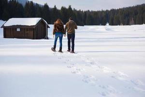 pareja divirtiéndose y caminando con raquetas de nieve foto