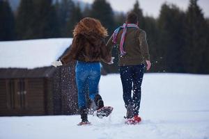 pareja divirtiéndose y caminando con raquetas de nieve foto