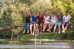 amigos disfrutando de la sandía mientras están sentados en el puente de madera foto