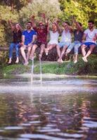 friends enjoying watermelon while sitting on the wooden bridge photo