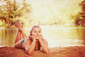 chica en bikini verde relajándose en la orilla del río foto