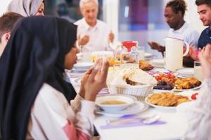 modern multiethnic muslim family praying before having iftar dinner photo