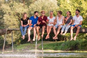 friends enjoying watermelon while sitting on the wooden bridge photo