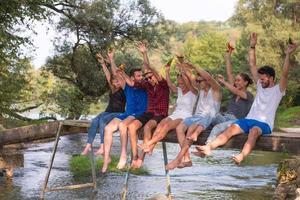 amigos disfrutando de la sandía mientras están sentados en el puente de madera foto