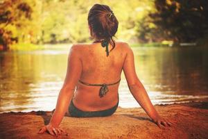 chica en bikini verde relajándose en la orilla del río foto