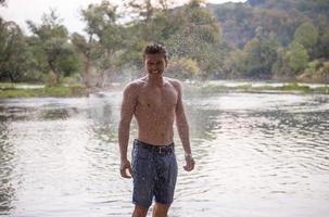 man with a bare torso splashing water photo