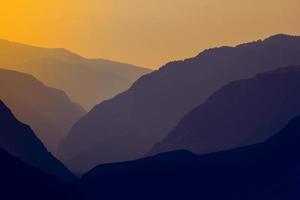 Silhouettes and outlines of a mountain massif in the setting sun photo