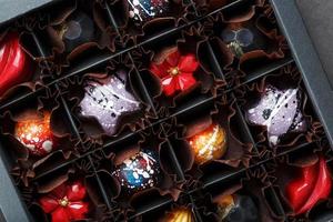 Colorful handmade chocolates in a box on a dark background photo