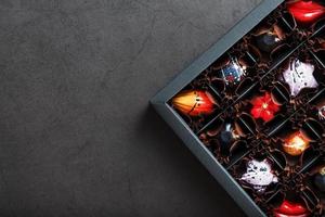 A set of colorful exclusive handmade chocolates in a box on a black background. photo