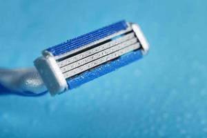 Razor blades on a blue background with drops of icy water photo