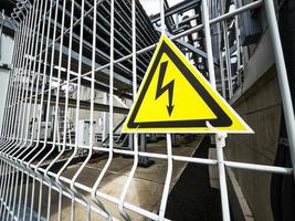 Danger Sign High voltage in a yellow triangle on a metal grid photo