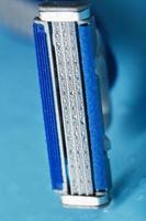 Shaving machine with three blades on a blue background with water drops in close-up photo