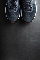 zapatos de correr negros con malla y cordones negros de cerca en un fondo oscuro foto