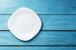 White square plate on a blue background top view. photo