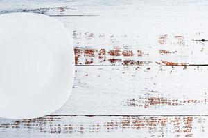 An empty round white plate on a blue wooden table. photo