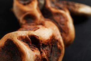 Textured curved Wooden snag of brown color with texture on a black background. photo