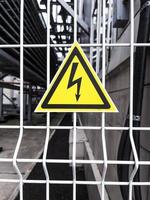 Danger Sign High voltage in a yellow triangle on a metal grid photo