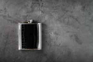 Steel flask in leather finish for alcohol on a dark background with copy space photo