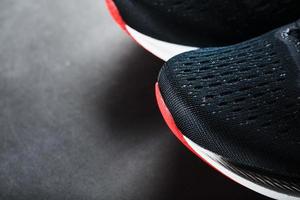 Black sports sneakers with red soles on a black background.
