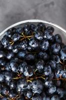 uvas negras dulces en un recipiente de metal sobre un fondo de textura oscura. foto