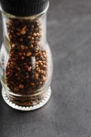 A mixture of seasonings, spices and herbs in a glass mill on a black background. photo