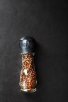 A mixture of seasonings, spices and herbs in a glass mill on a black background. photo