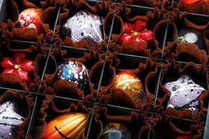 Colorful handmade chocolates in a box on a dark background photo