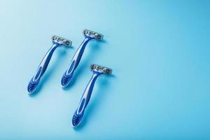 máquinas de afeitar azules en una fila sobre un fondo azul con cubitos de hielo foto