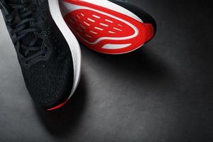 Black sports sneakers with red soles on a black background.
