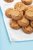 A bunch of oatmeal cookies with chocolate on a napkin on a blue background photo