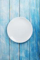 An empty round white plate on a blue wooden table. photo