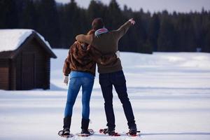 pareja divirtiéndose y caminando con raquetas de nieve foto