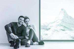 young couple sitting on the floor near window at home photo