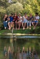 friends enjoying watermelon while sitting on the wooden bridge photo