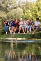 friends enjoying watermelon while sitting on the wooden bridge photo